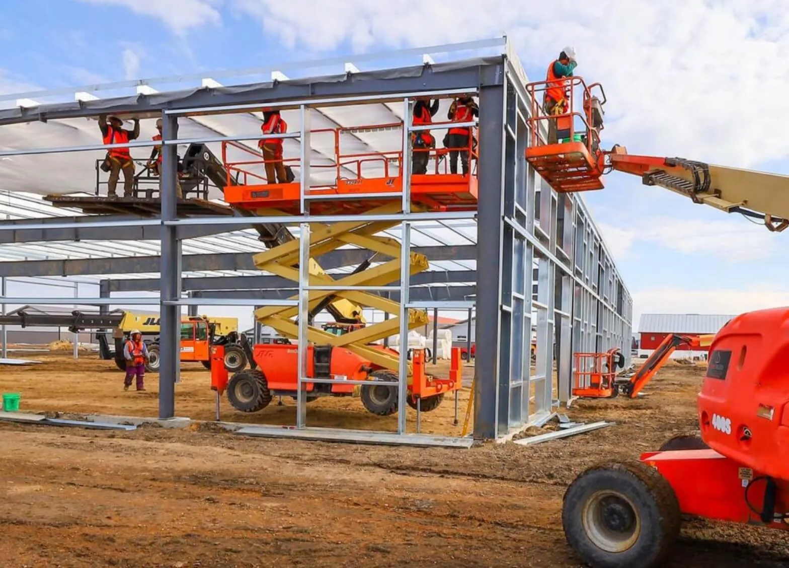 Red-iron rigid steel frames of a commercial building under construction against a clear sky