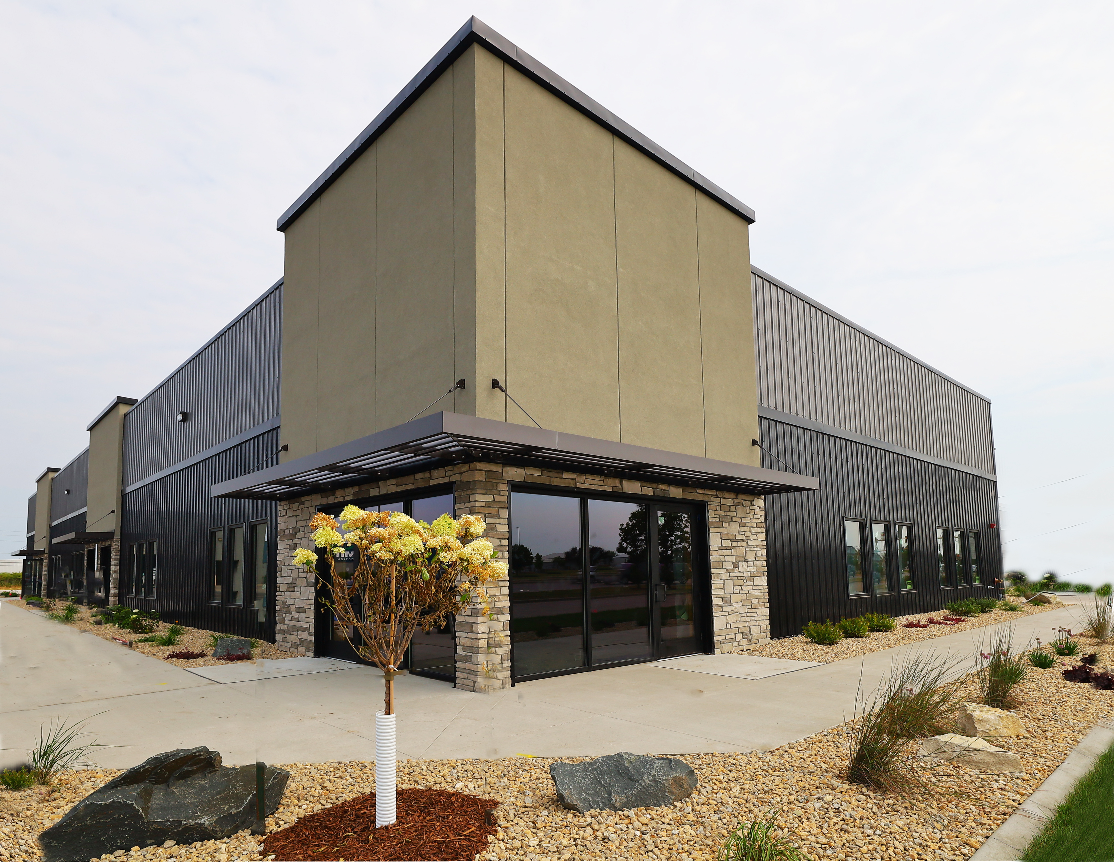 North Fargo office building with dark metal siding, stone entrances, and landscaped frontage